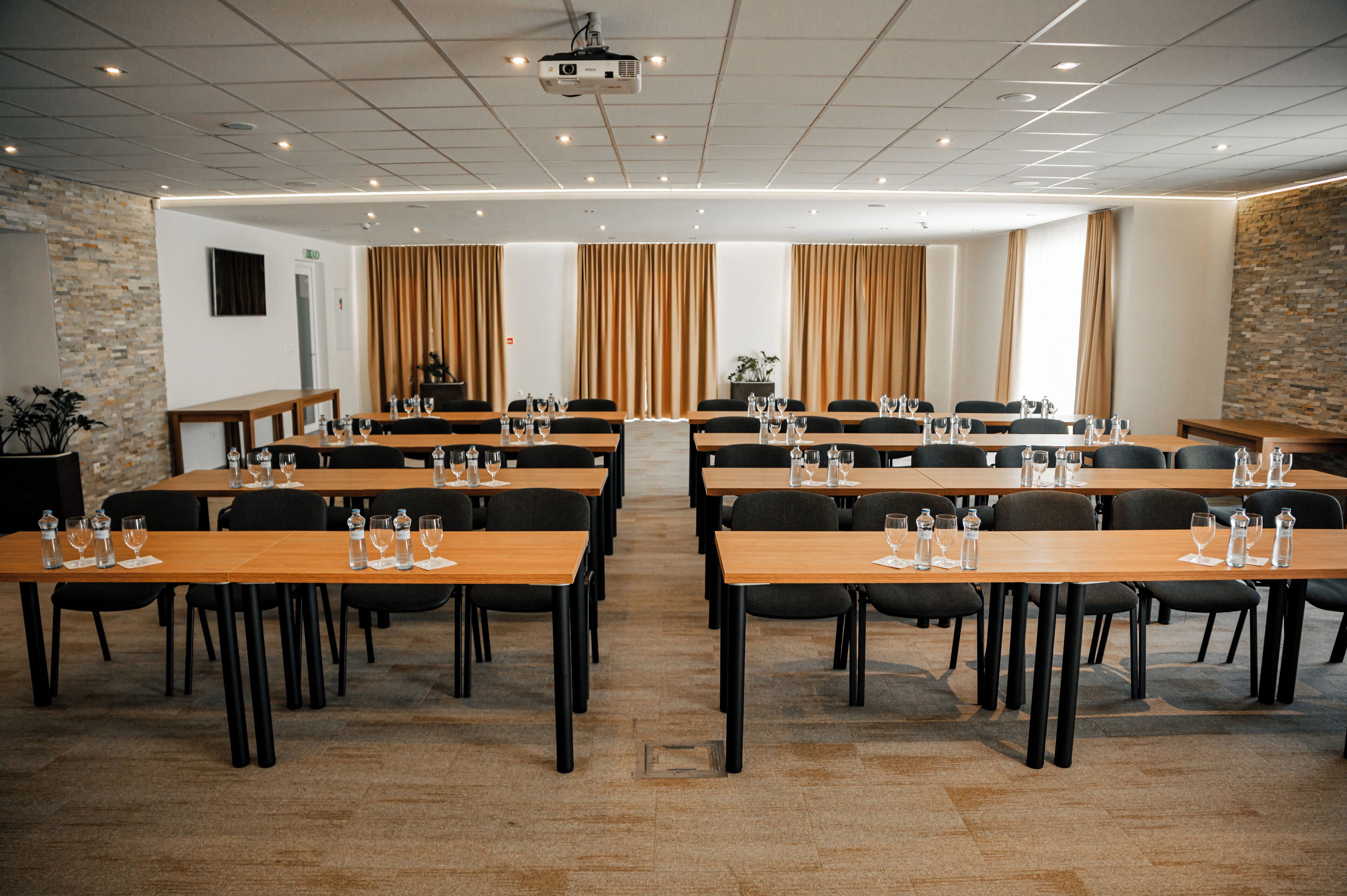 Ein Konferenzraum mit mehreren Tischen, Stühlen und einer Projektionsleinwand.