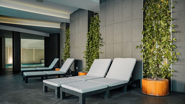 Een moderne, overdekte ontspanningsruimte met lounge fauteuils en verticale tuinen.