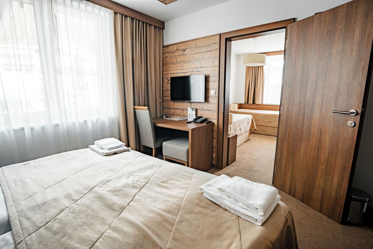 Een hotelkamer met een bed, een bureau met stoel, een televisie en een badkamer door een open deur zichtbaar.