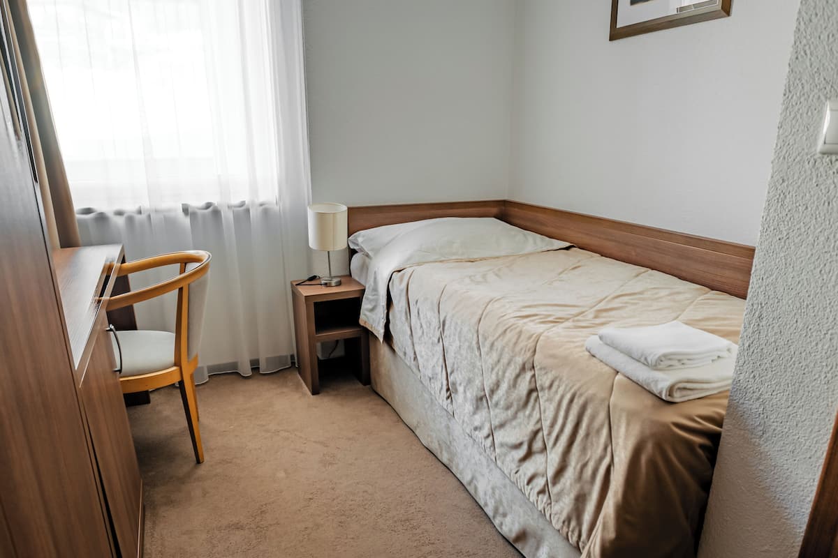Een keurig opgemaakt hotelkamer met een bed, bureau en stoel.