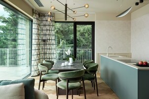 Una cucina moderna con zona pranzo, ampie finestre e vista sugli alberi.