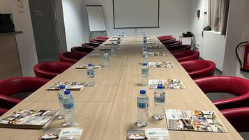A conference room with a long table, red chairs, water bottles, and brochures.