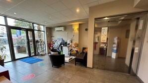 A reception area with a desk, chairs, a teddy bear, and an elevator.