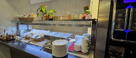 A buffet counter with various food items, a coffee machine, and a plant.
