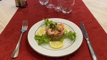 A plate of shrimp salad on a table with a red tablecloth.