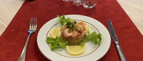 Un plato de ensalada de camarones sobre una mesa con mantel rojo.