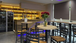 A restaurant with a bar area, round tables, and chairs.
