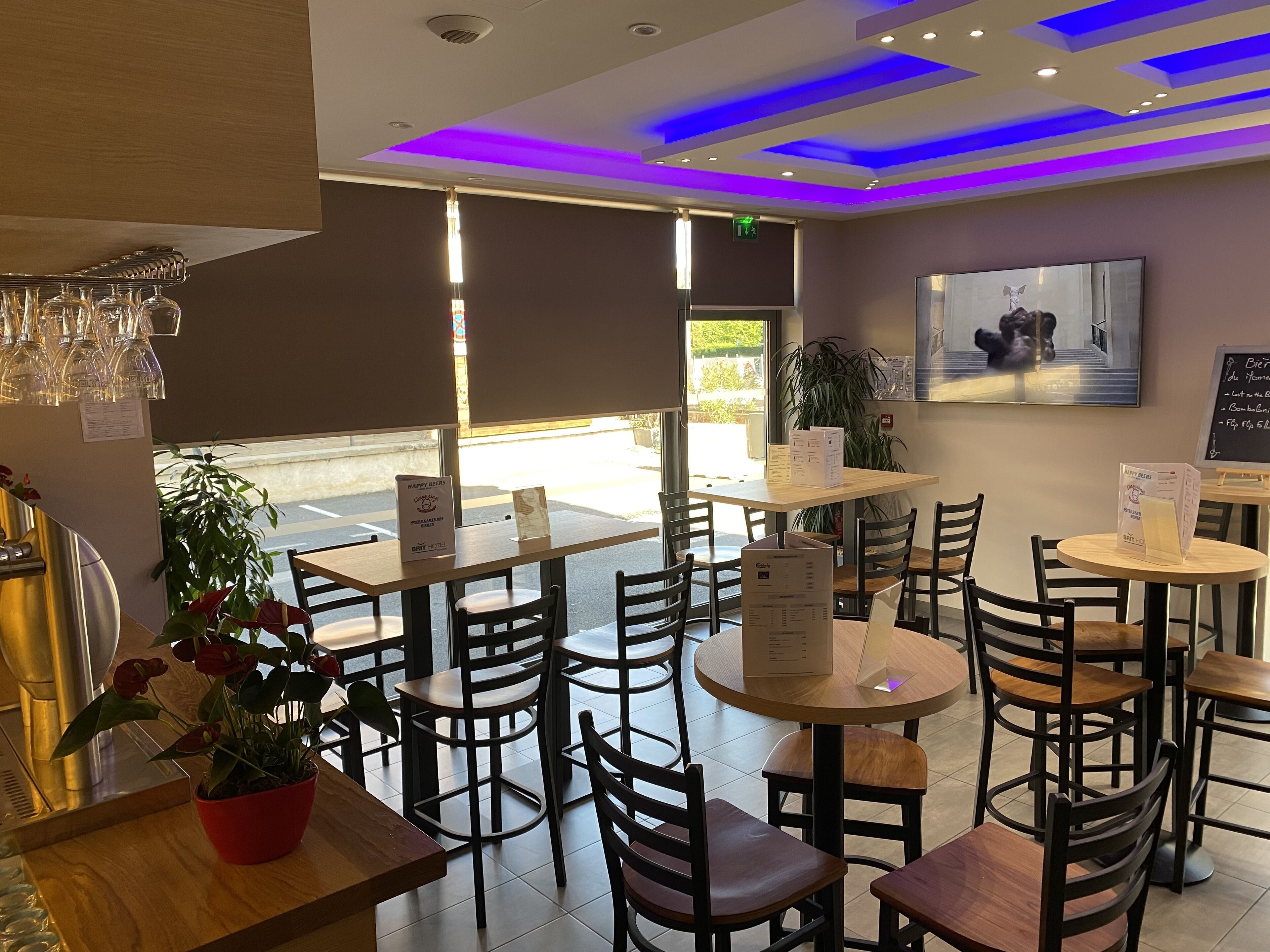 A restaurant interior with tables, chairs, and a menu stand.