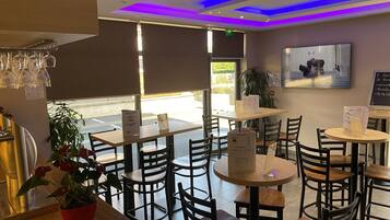 Interior de un restaurante con mesas, sillas y un atril para el menú.