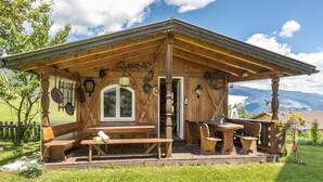 A rustic wooden building with a covered patio, benches, and a table. - Hotel Alpenfrieden (Rio di Pusteria)
