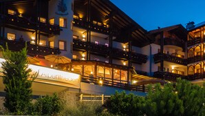 A multi-story hotel with balconies, a sign indicating it is an alpine hotel, and a well-lit facade. - Hotel Alpenfrieden (Rio di Pusteria)