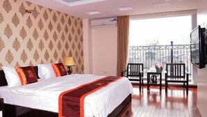 A hotel room with a large bed, a balcony with a view, and a TV mounted on the wall. - Mely Hotel (Hanoi)