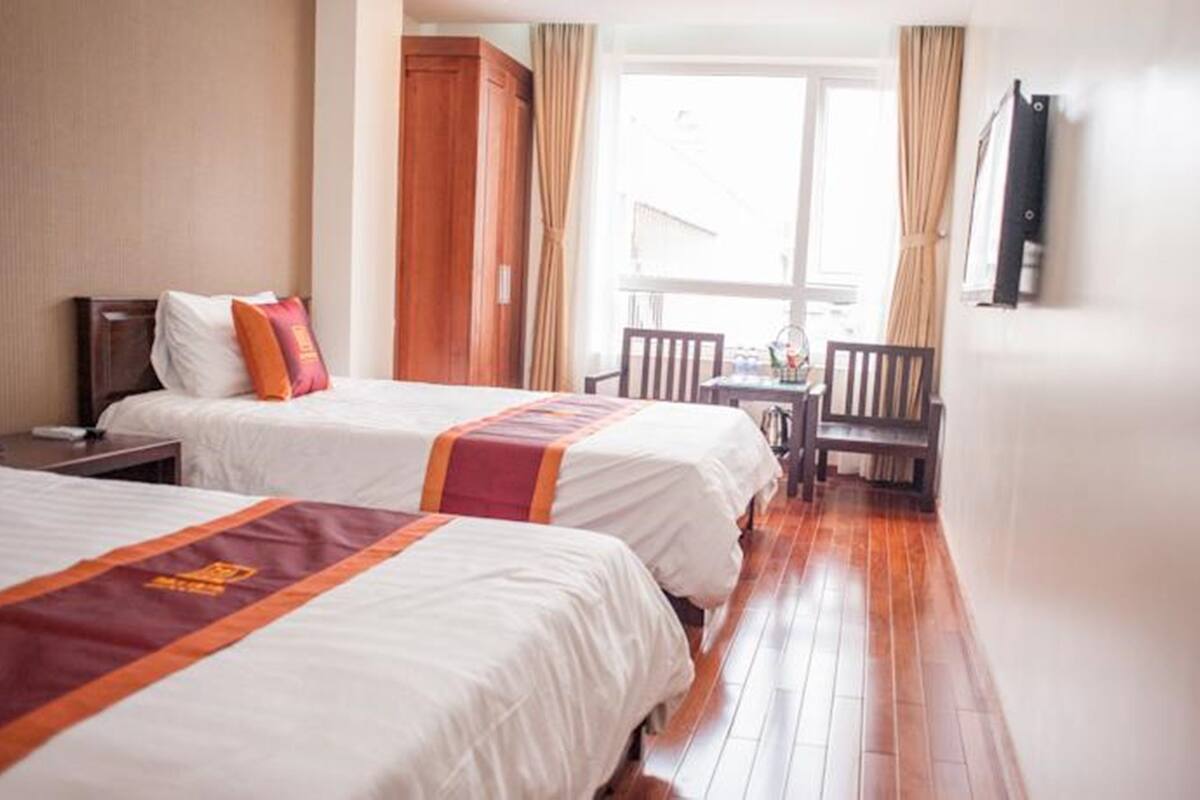 A hotel room with two beds, a desk, and a chair.