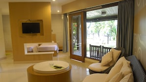 A modern hotel room with a bed, a sofa, a round coffee table, and a TV mounted on the wall. - Putri Duyung Ancol (Jakarta)