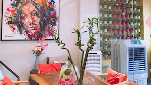 A modern dining area with a wooden table, red cushions, a large abstract painting, and a wall-mounted plant display.