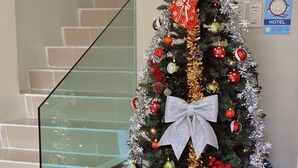 A Christmas tree with a large bow, red and gold ornaments, and a 'Merry Christmas' sign.