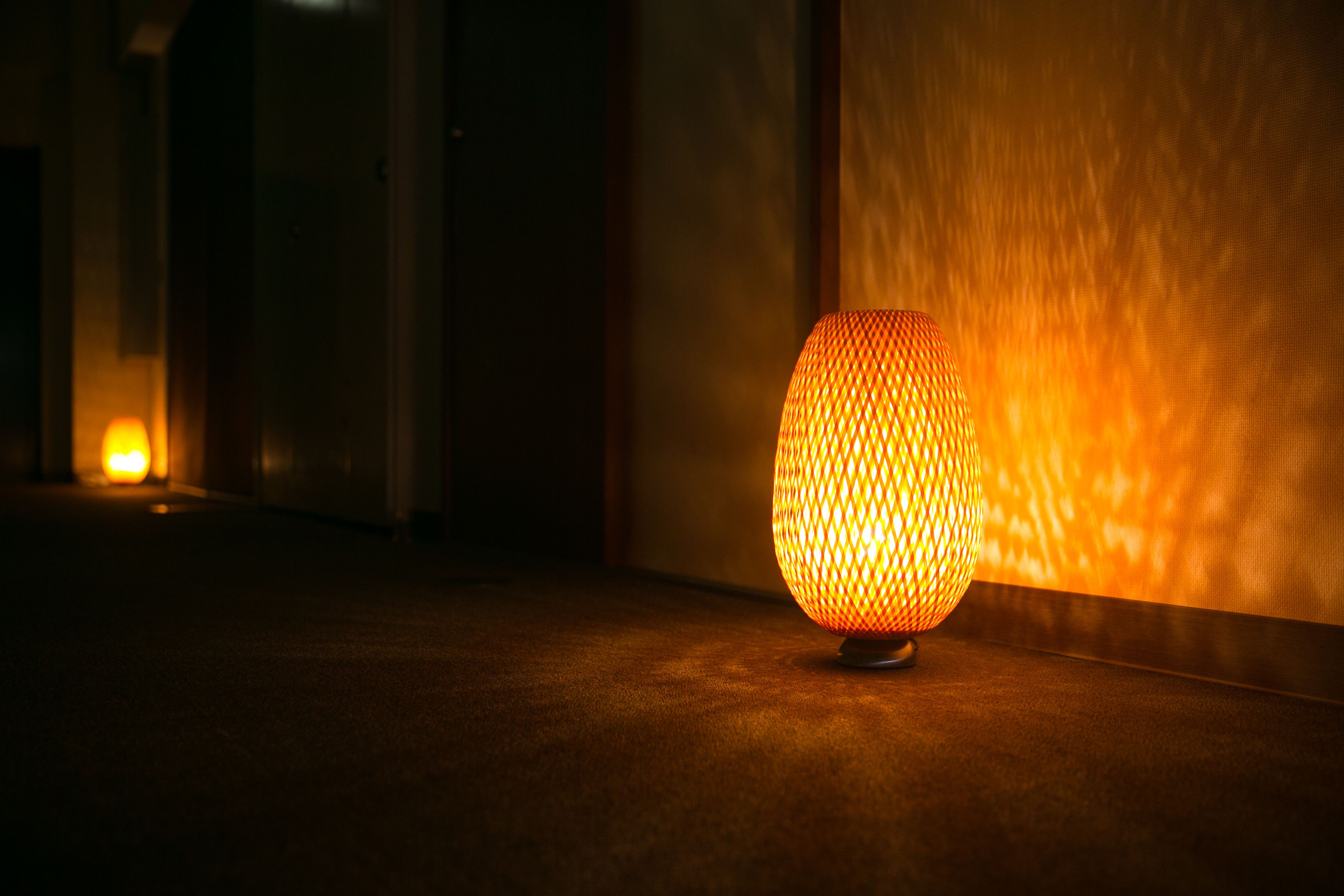 Una lámpara esférica y texturizada sobre el suelo en un pasillo tenuemente iluminado.