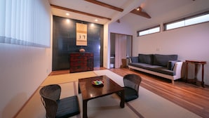 A modern living room with a sofa, a dining table with chairs, a wooden cabinet, and a large window. - Kunisakiso (Beppu)