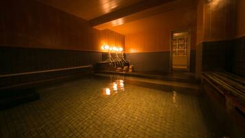 Una piscina coperta scarsamente illuminata, con pareti piastrellate e una panchina lungo il bordo.