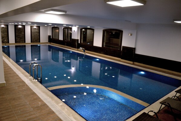 Una piscina interior con agua cristalina, paredes y suelo de azulejos.