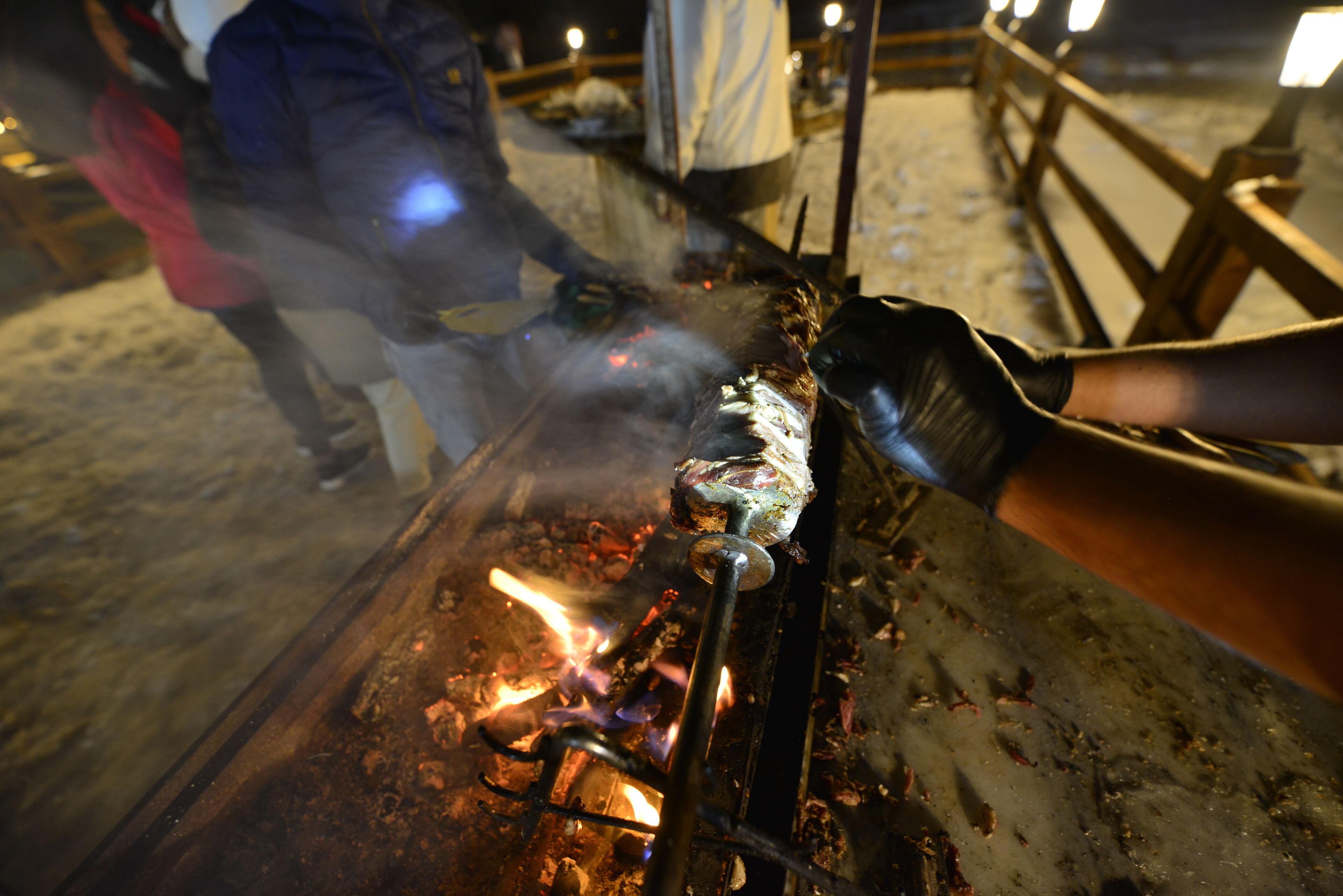 A grill with visible flames and smoke, indicating active cooking.