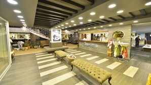 Een hotel lobby met een receptiebalie, een trap en zitgedeeltes.