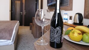 Een hotelkamer met een bed, een fles wijn, een wijnglas en een schaal fruit.