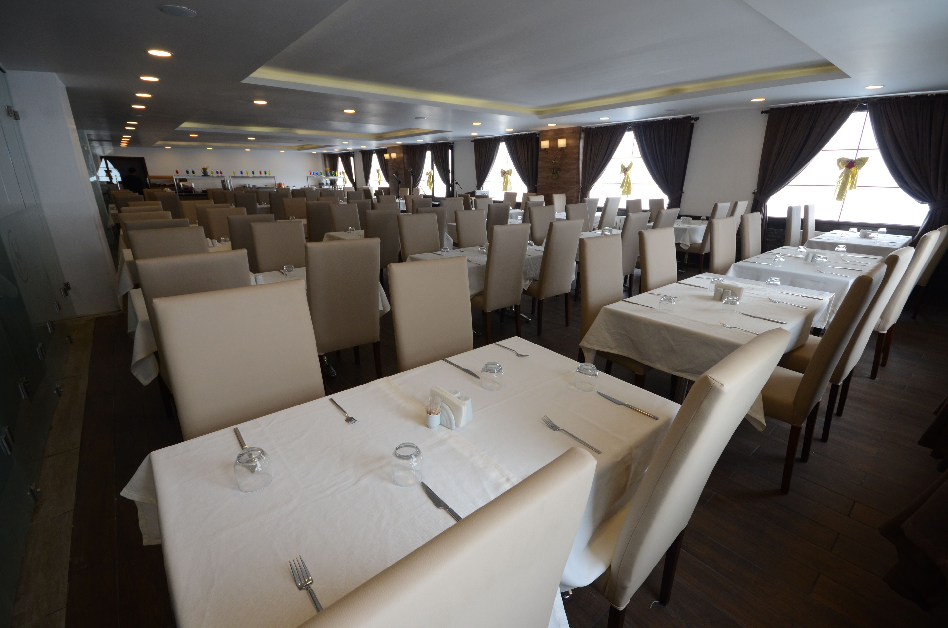 A restaurant with multiple tables and chairs, arranged in rows.