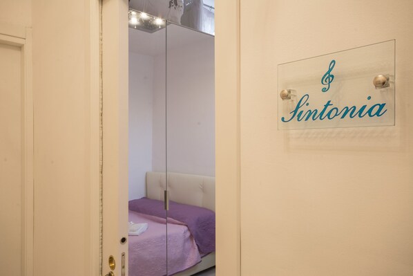 Una habitación con una cama, un espejo y un letrero que dice "Sintonia".
