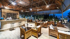 Un área de bar al aire libre con mobiliario de madera y un fondo de pared de piedra.