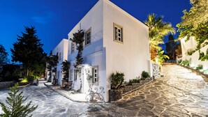 Un edificio blanco con un patio empedrado de piedra, un pequeño jardín y una escalera que conduce a la entrada.