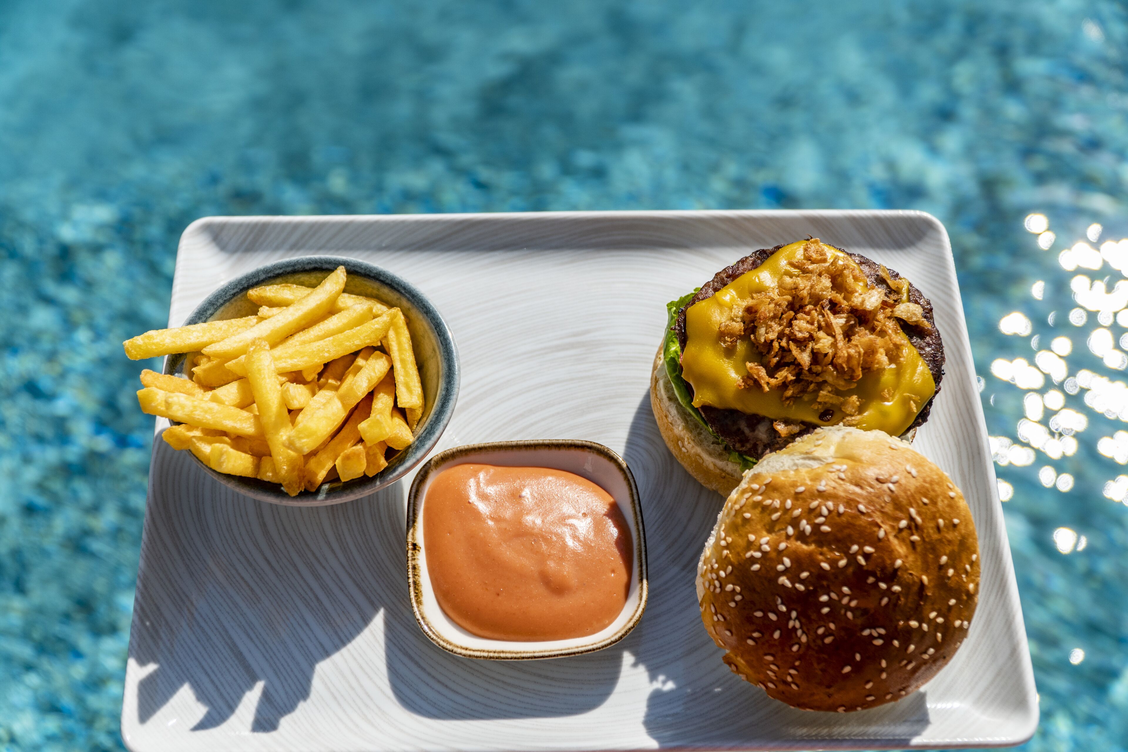 Un plateau avec des frites, un hamburger et un petit bol de sauce.