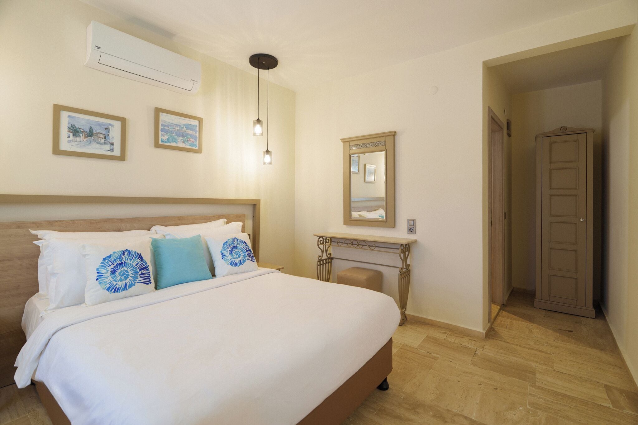 A hotel room with a large bed, a bedside table, a mirror, and an air conditioning unit.