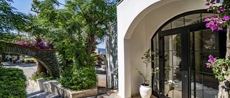 A modern building with a stone archway, a large potted plant, and a glass entrance.
