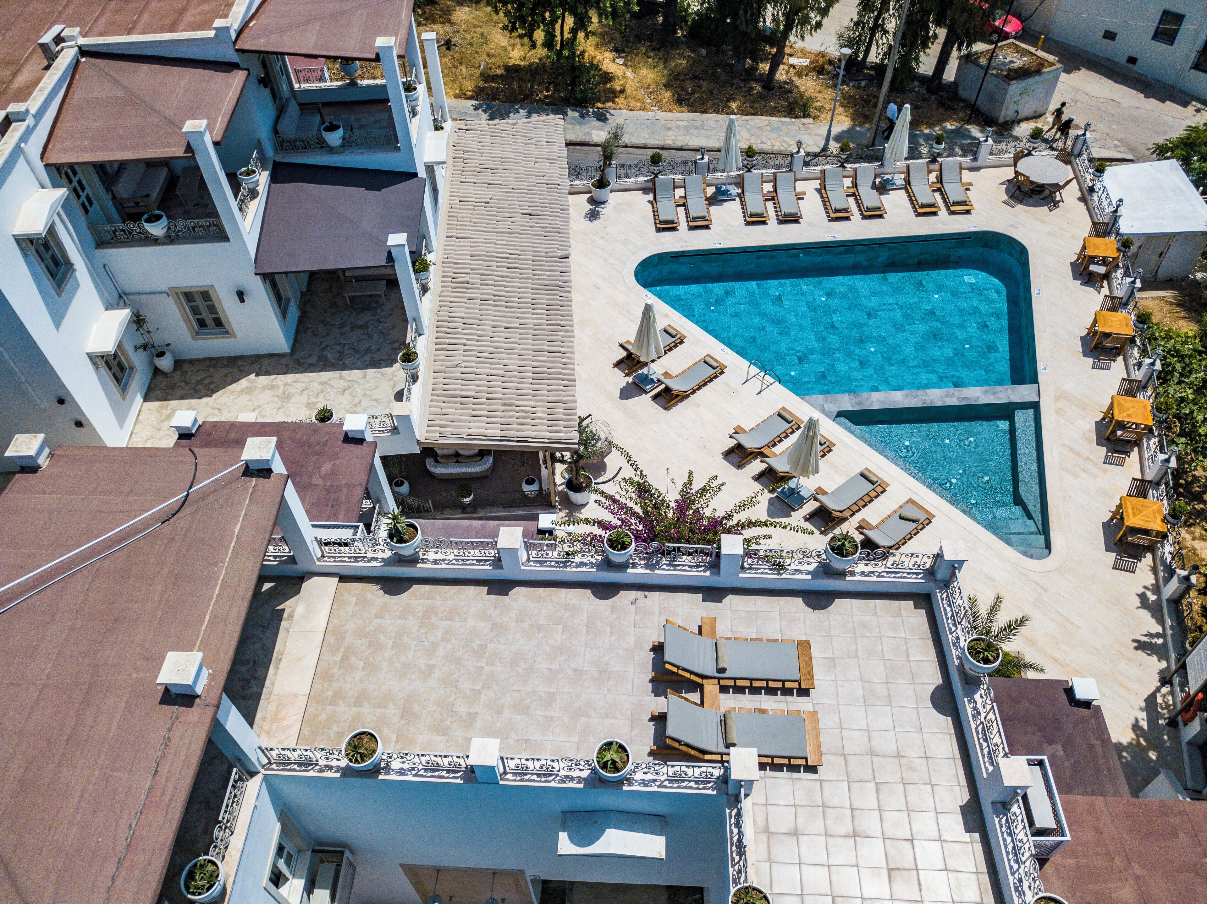 An aerial view of a hotel with a swimming pool, sun loungers, and outdoor seating areas.