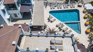 An aerial view of a hotel with a swimming pool, sun loungers, and outdoor seating areas.