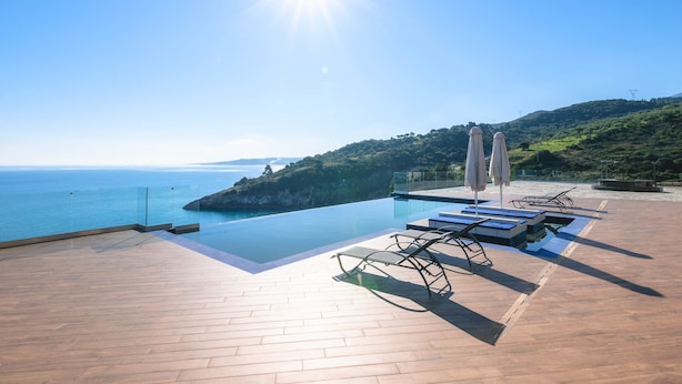 A rooftop infinity pool with a clear view of the sea, lounge chairs, and umbrellas. - Orient Villas (Zakynthos)