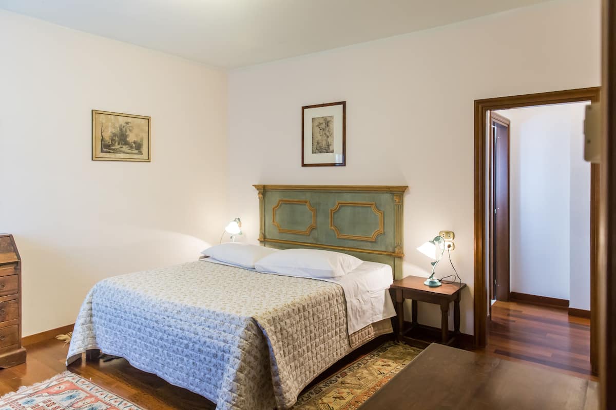 Un dormitorio con cama, cómoda, mesita de noche y dos cuadros en la pared.