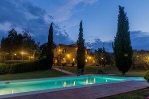 Una piscina al aire libre, sombrillas, sillones reclinables de piscina