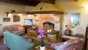 Ein gemütliches Wohnzimmer mit Kamin, floralen Sofas und einem Fernseher.