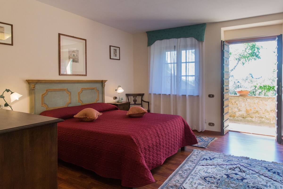 Un dormitorio con cama de madera, un escritorio, una silla, una mesita de noche y una ventana con vistas al exterior.