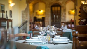 Ein Esstisch, gedeckt mit Tellern, Gläsern und Besteck, in einem Restaurant mit Backsteinbogen und warmer Beleuchtung.