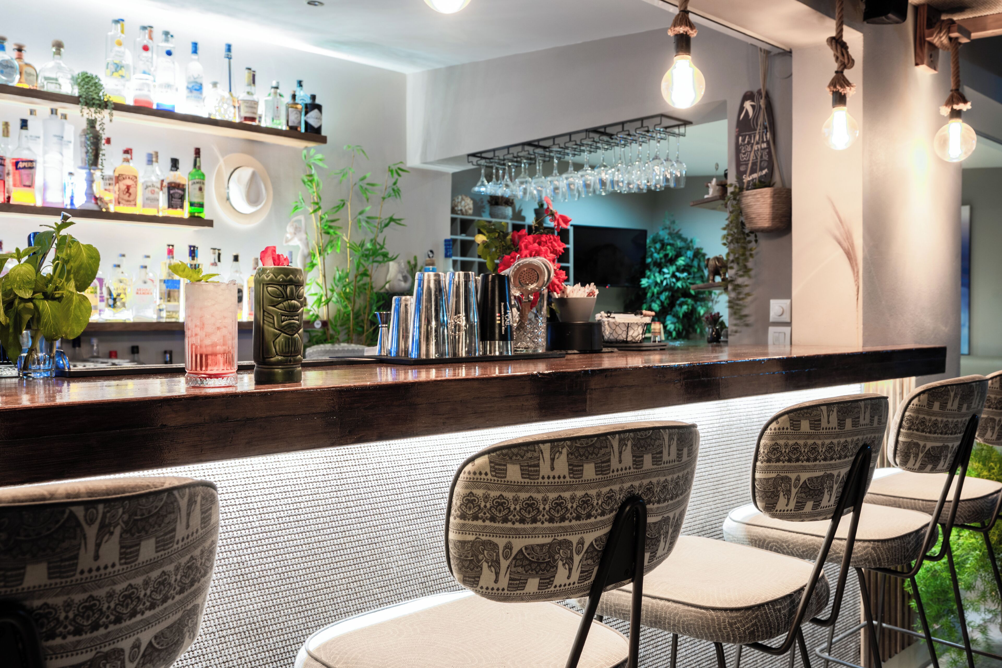 Zona de bar con mostrador, sillas y estantes llenos de botellas.