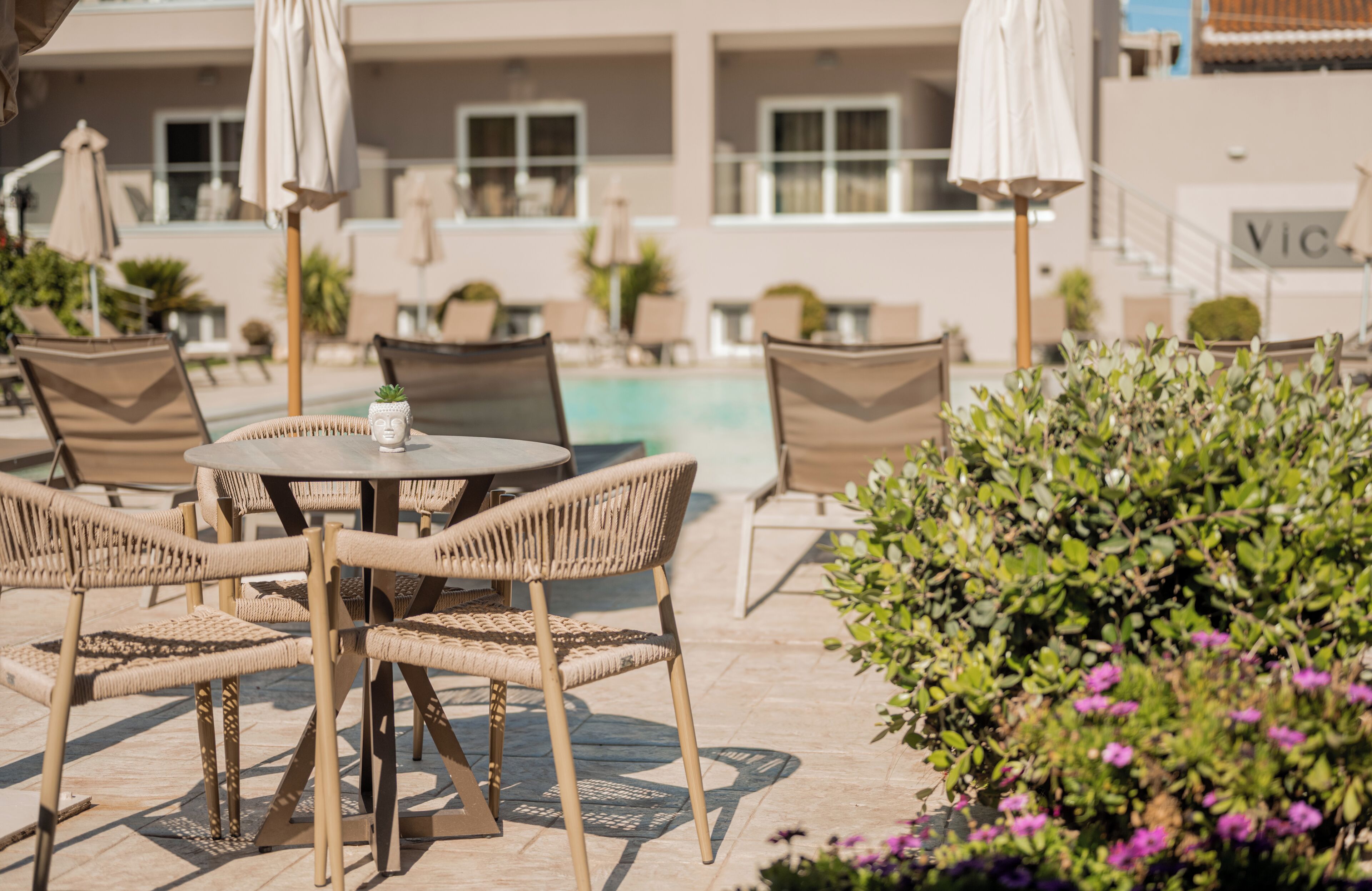 An outdoor seating area with wicker chairs and tables, a pool, and umbrellas.