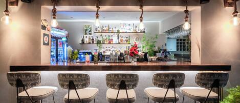A bar area with a counter, hanging light fixtures, and bar stools.