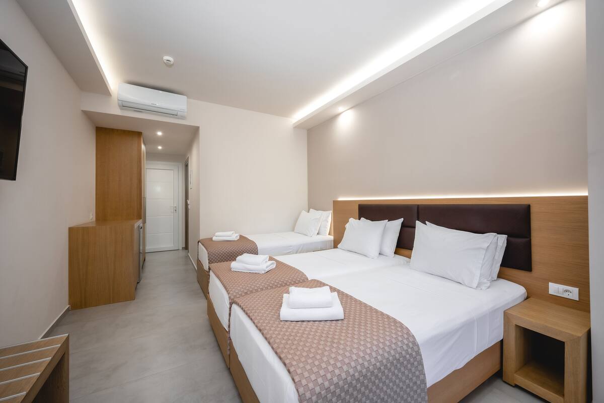 Una habitación de hotel con dos camas, un escritorio de madera y televisión integrada.