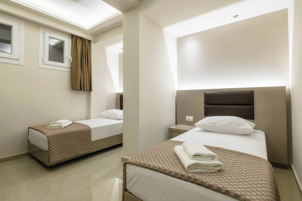 Una habitación de hotel con dos camas, una ventana con cortinas y un diseño moderno.