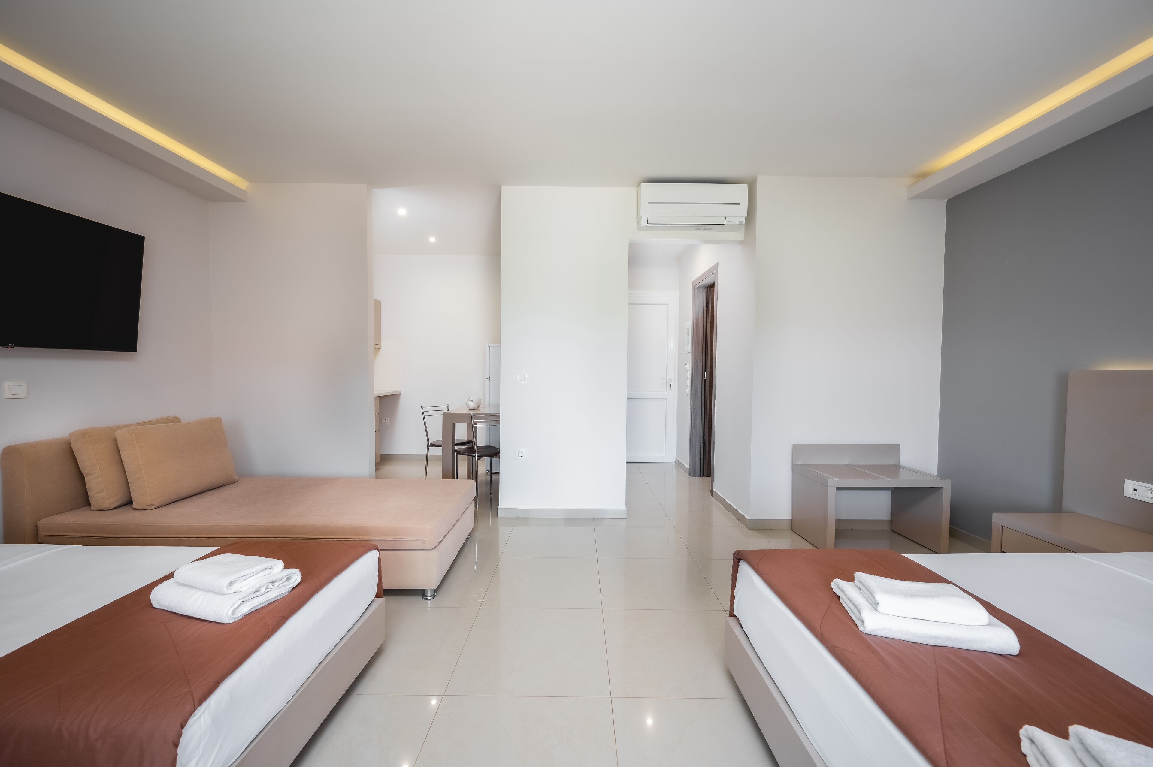 Une chambre d’hôtel avec deux lits, un canapé, un bureau, une télévision et un appareil de climatisation.