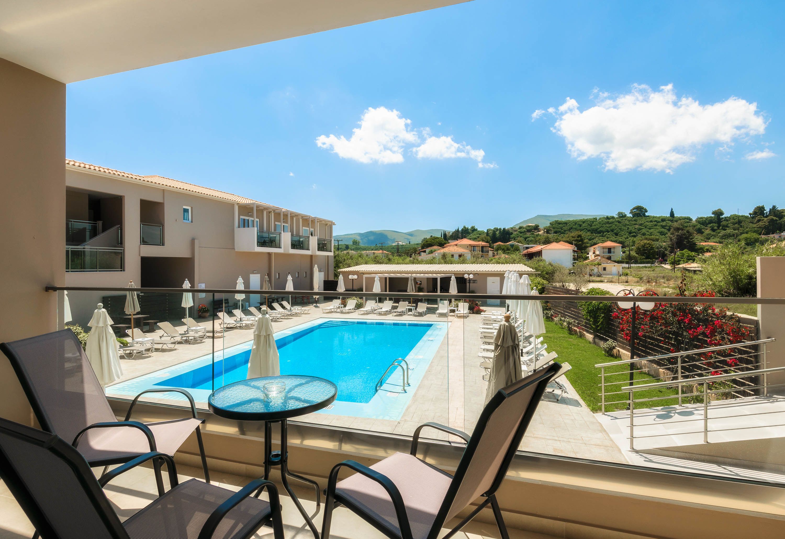 A balcony with a pool, lounge chairs, and a table.