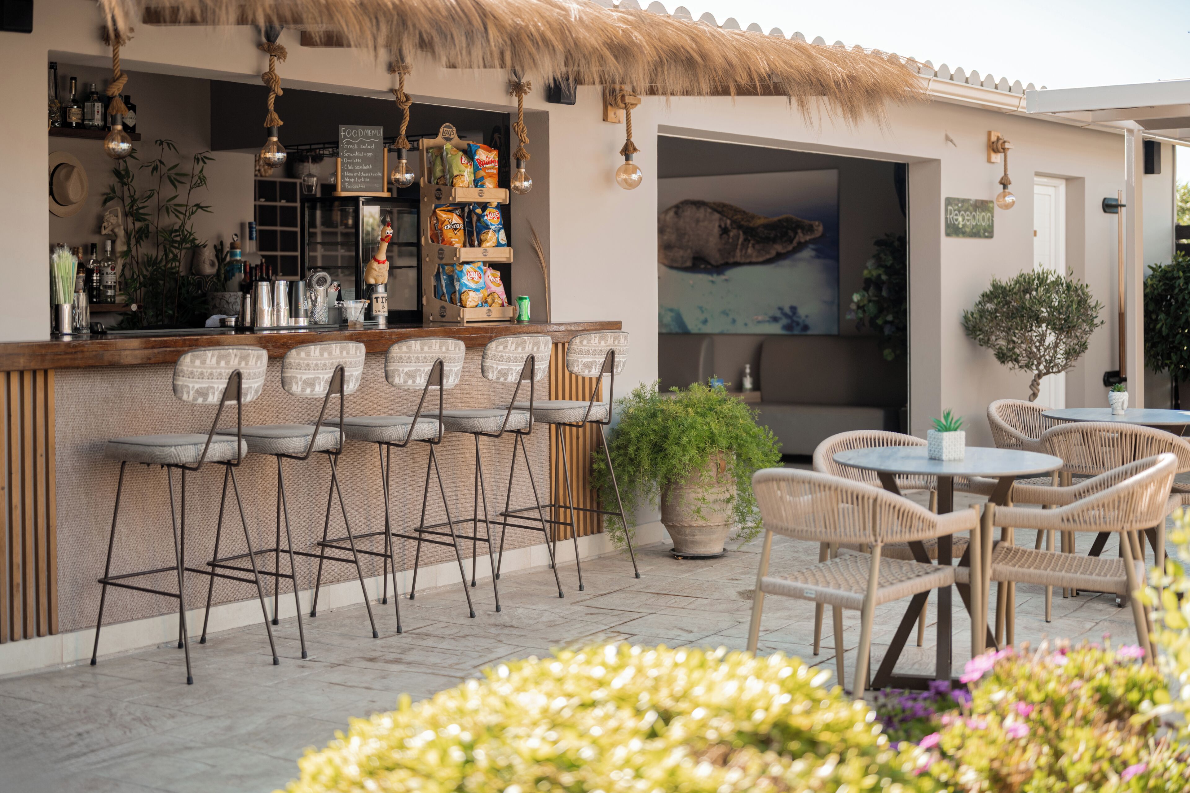 An outdoor bar area with wicker chairs and a thatched roof.